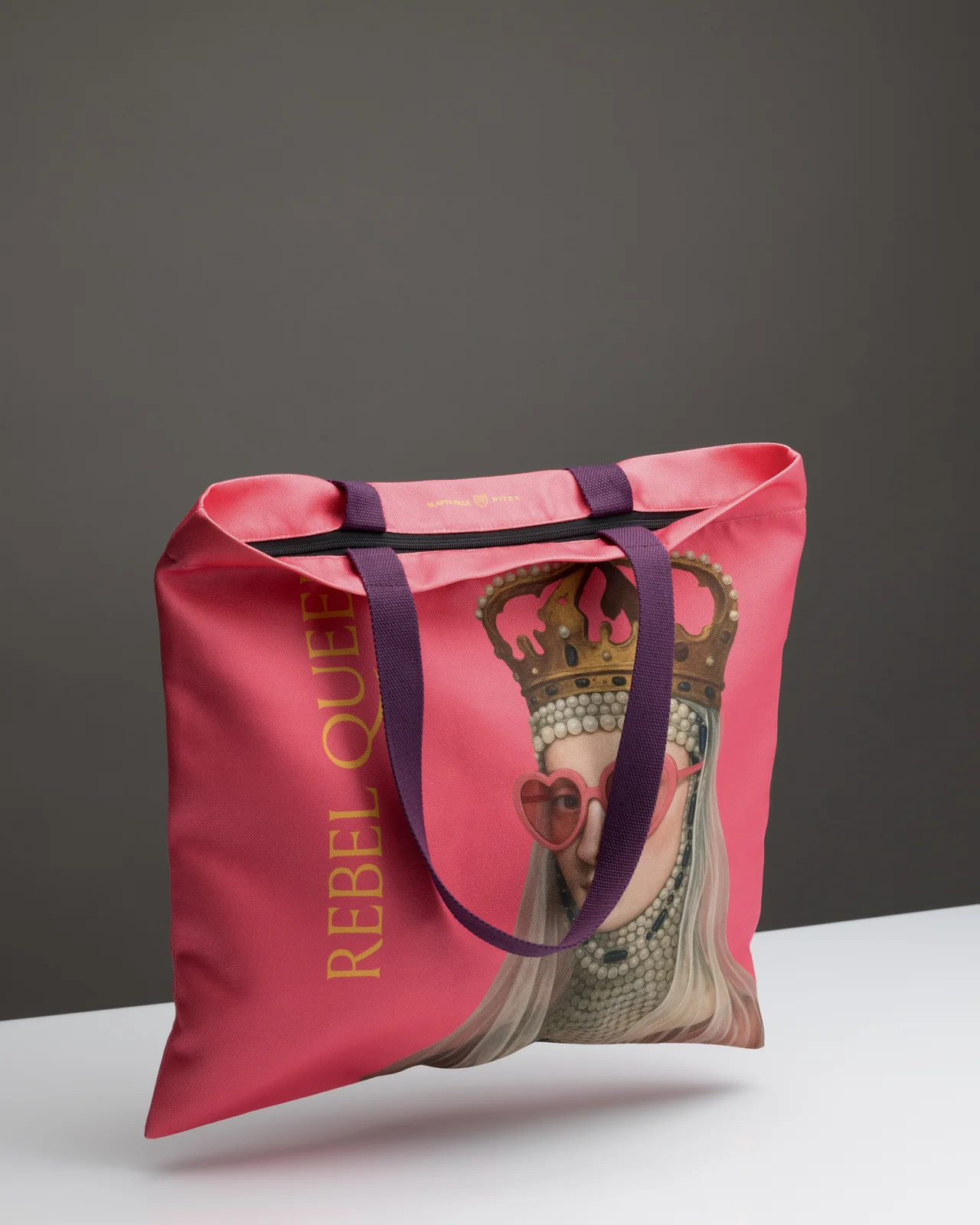 Pink “Rebel Queen” shopping bag from the “Rebel Queen” gift on a white table, angled view
