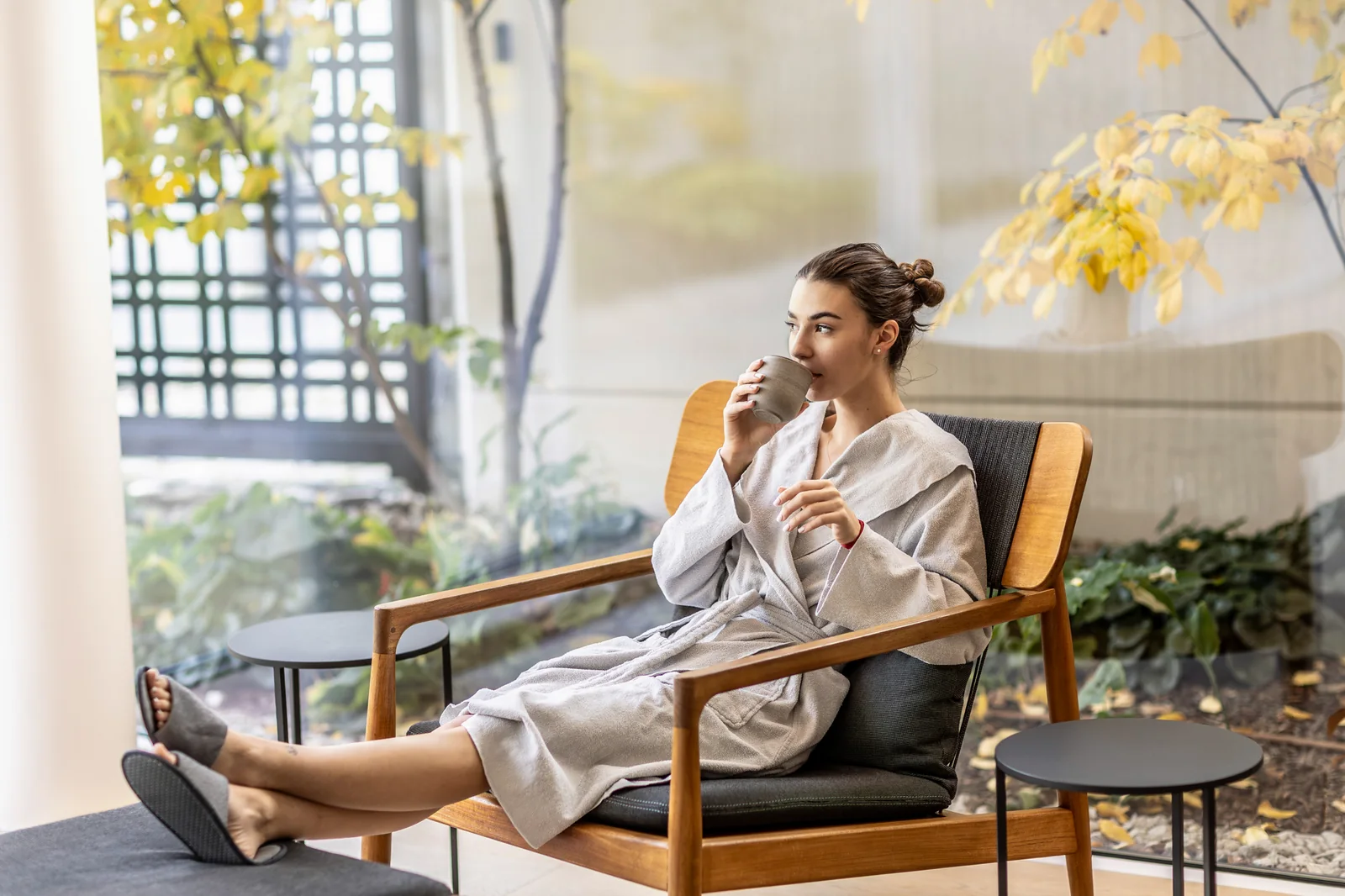 Woman in a robe drinking from a cup in an armchair by a courtyard – “Queen Catherine's Spring” ritual