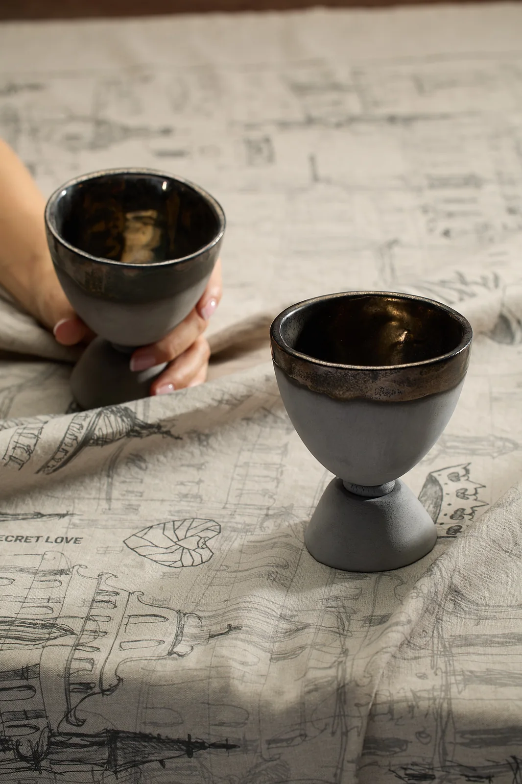 Two black ceramic goblets on a “Royal Vilnius Love Story” linen tablecloth