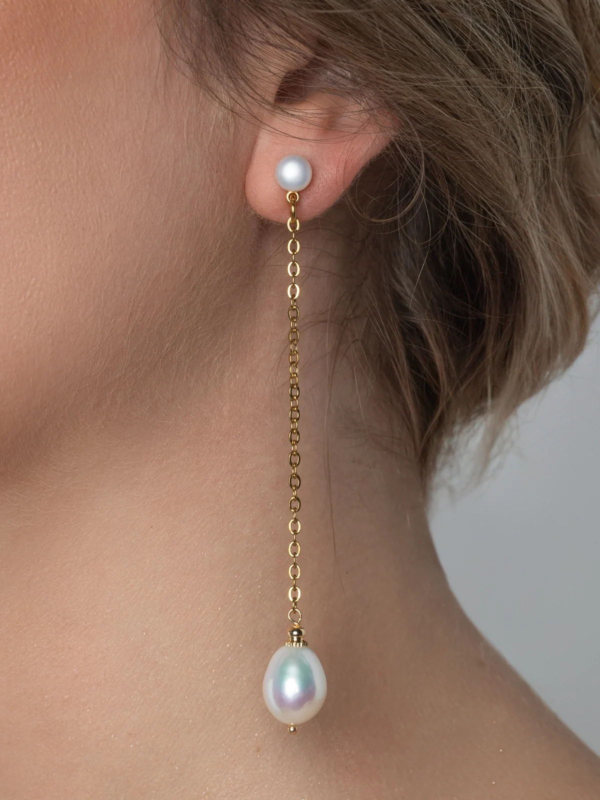 Earring “The Queen's Pearl” with a long chain and a teardrop pearl on a model's ear