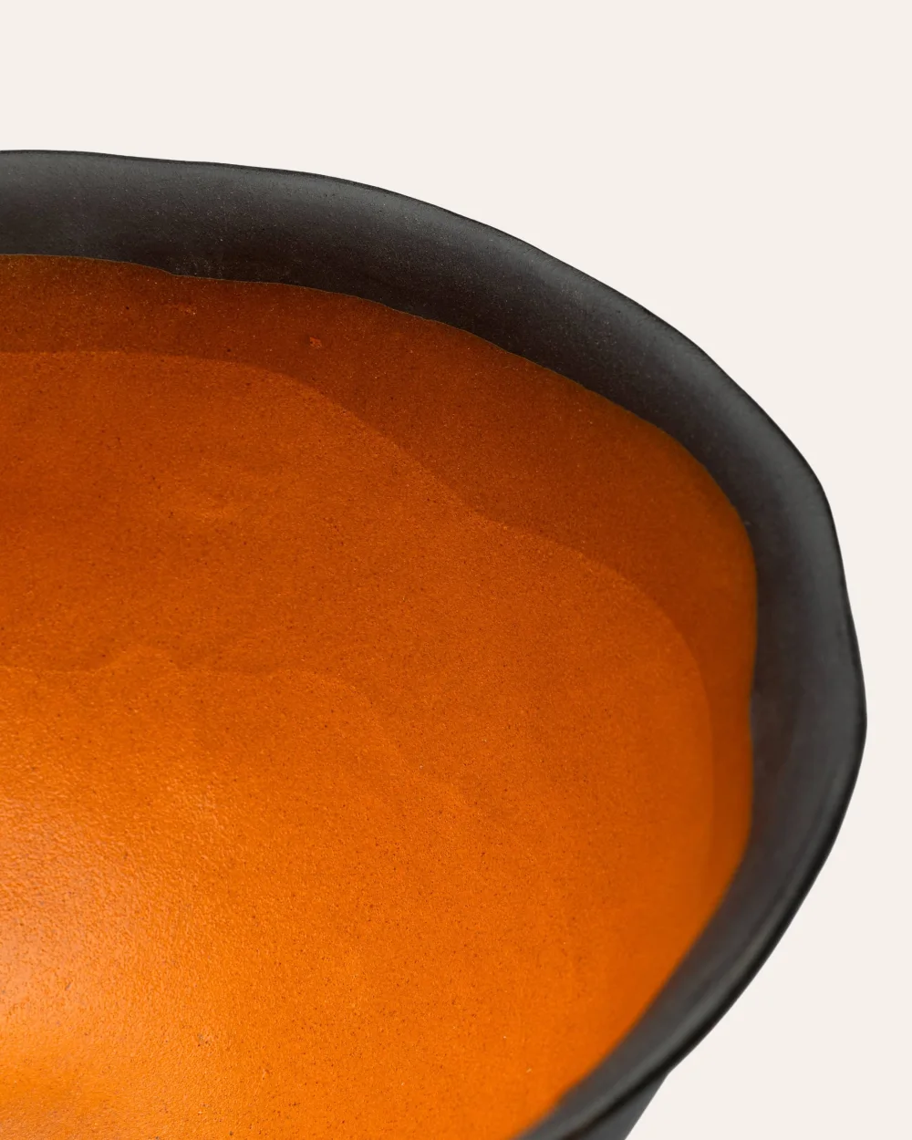 Karalių dubens ant kojelės oranžinės vidinės glazūros ir juodo krašto detalė iš arti