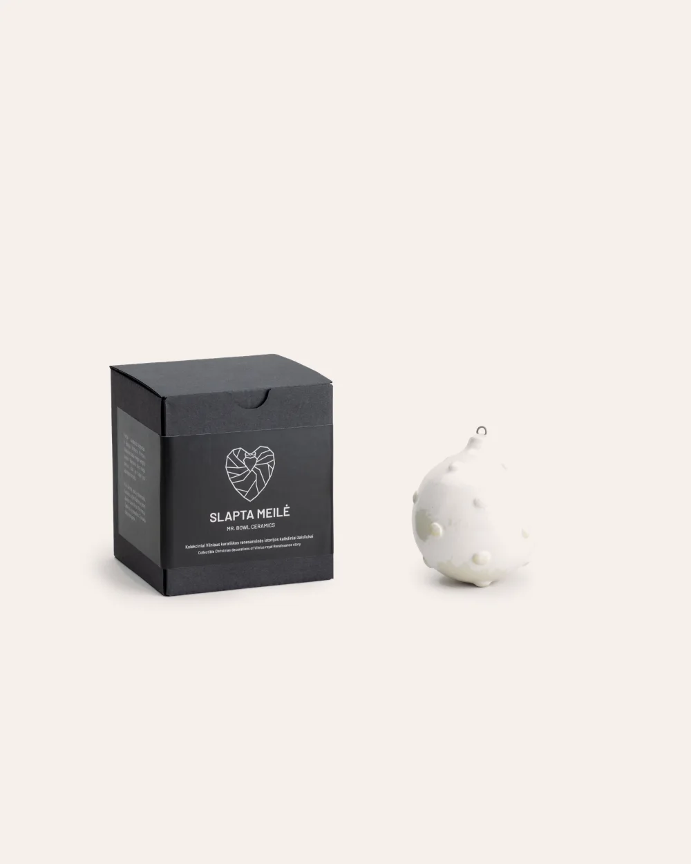 “Royal Pearl” Christmas ornament next to a black “Slapta meilė” box