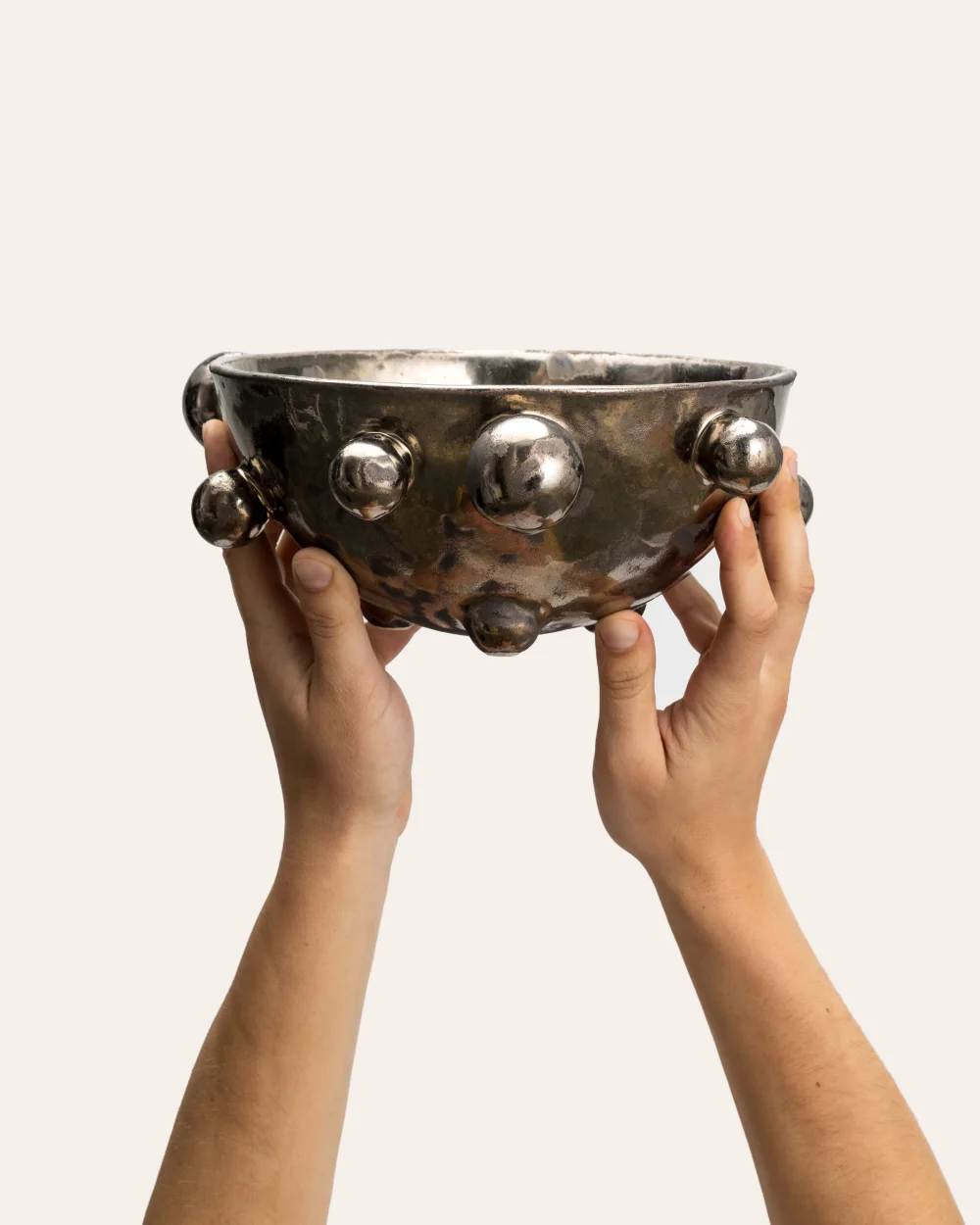 Medium dark gold “The Queen's Pearl Bowl” held in two hands, side view