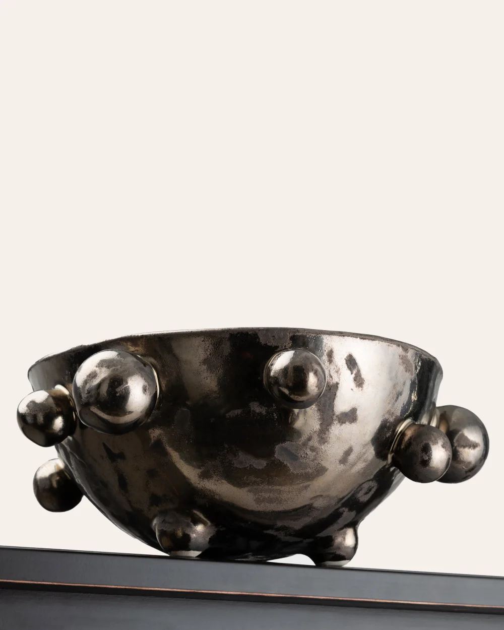 Side of a medium dark gold “The Queen's Pearl Bowl” on the edge of a shelf