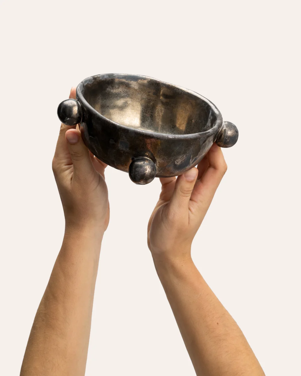 Small dark gold “The Queen's Pearl Bowl” in two hands, front view