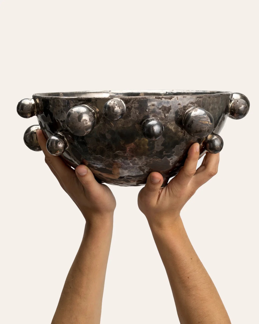 Large dark gold “The Queen's Pearl Bowl” in two hands, side view