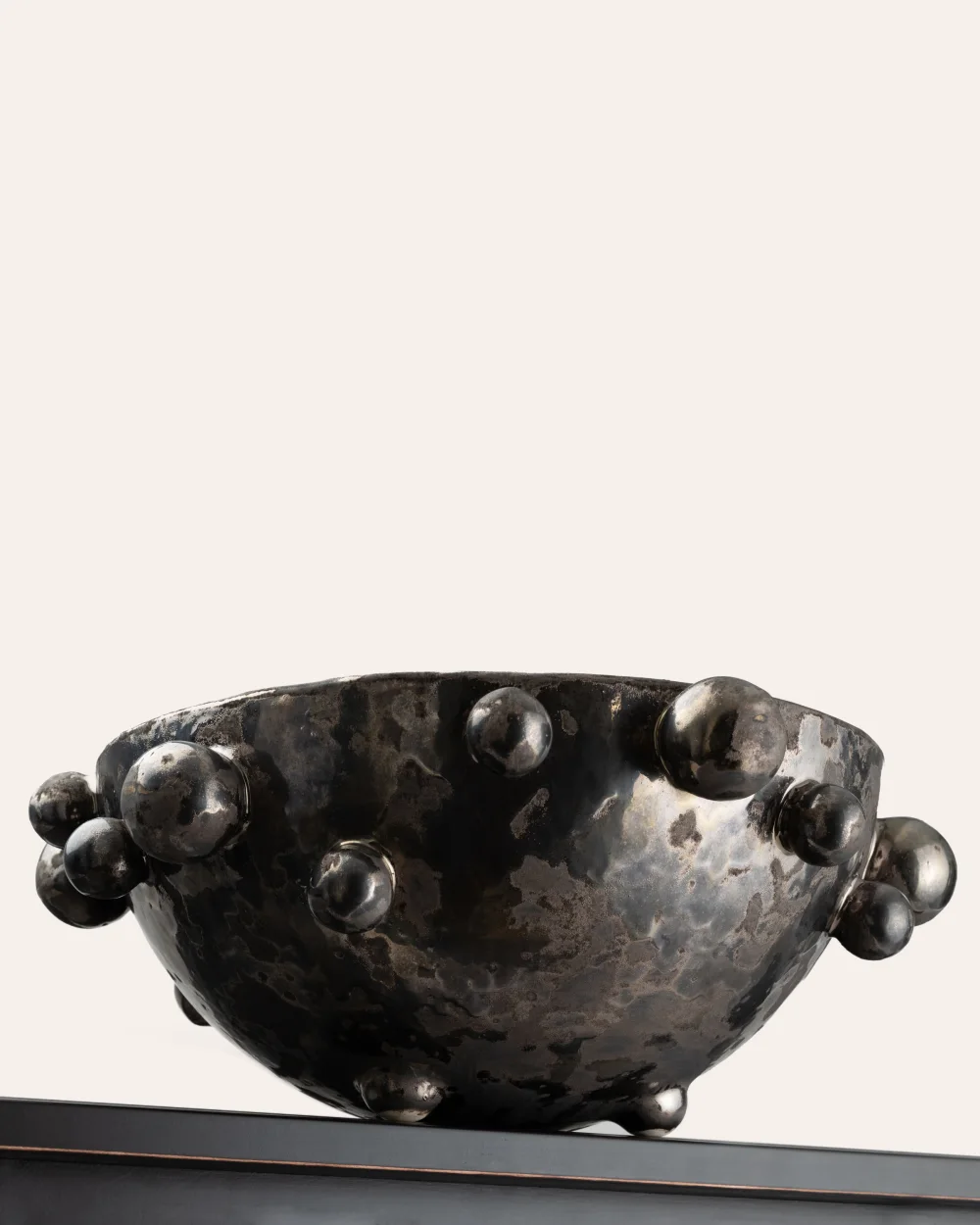 Side of a large dark gold “The Queen's Pearl Bowl” on the edge of a shelf
