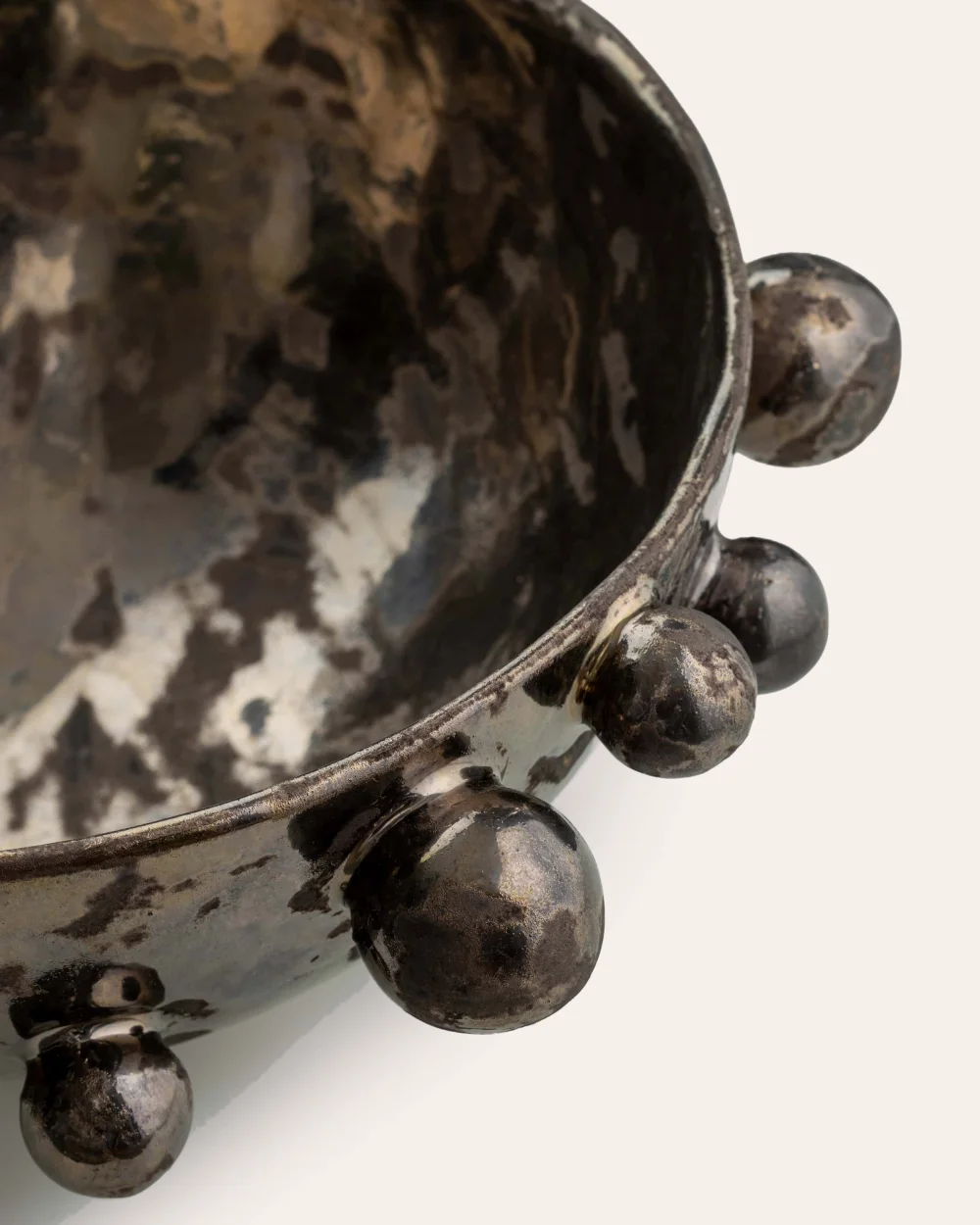 Close-up of the rim and beads of a dark gold “The Queen's Pearl Bowl”