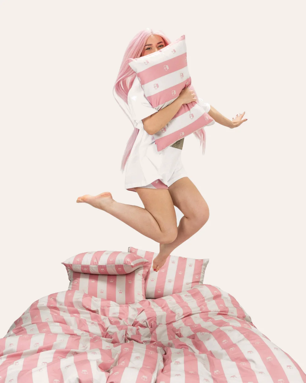 Girl with a pillow jumping above pink striped “Your Majesty” bedding