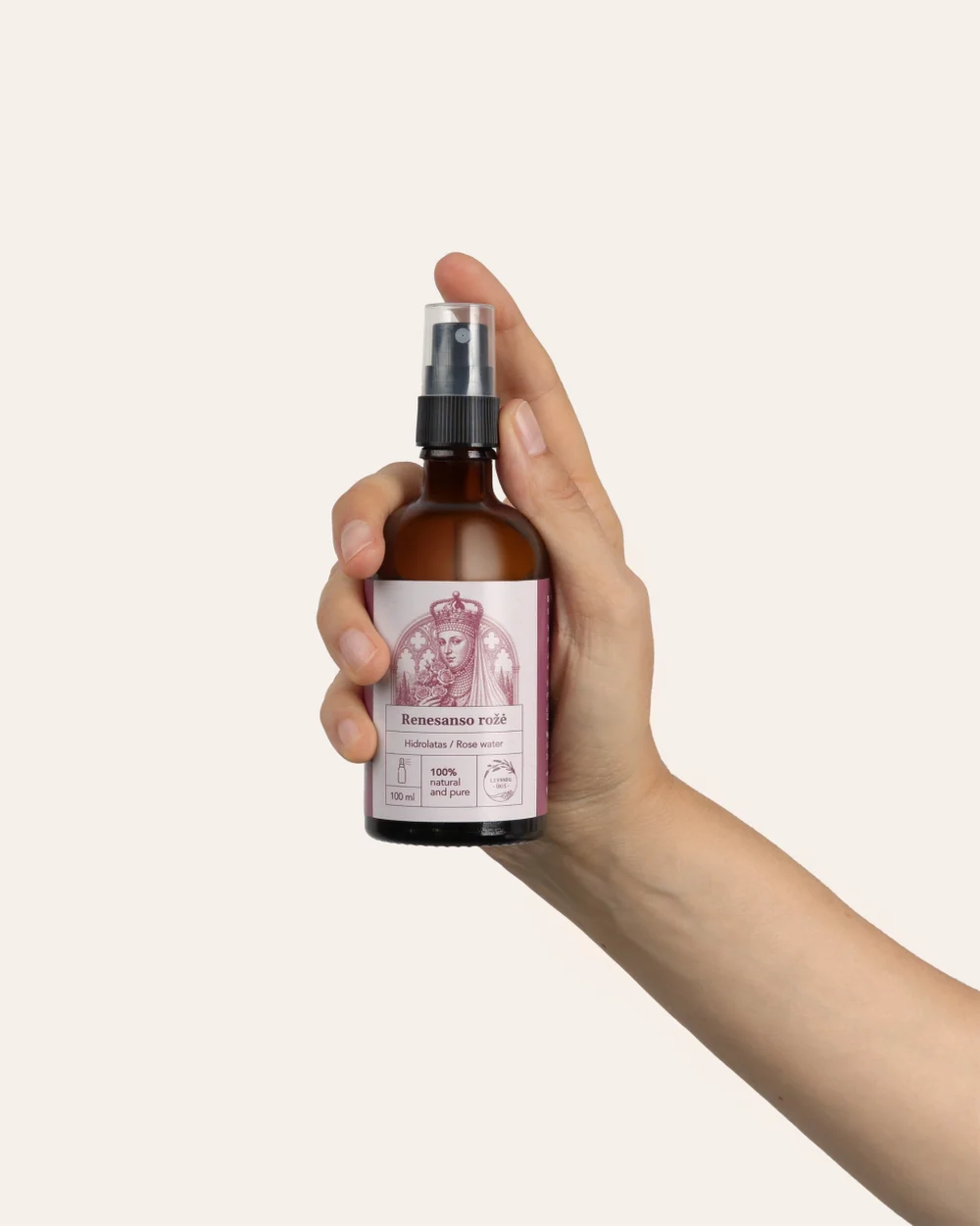 A bottle of “Renaissance Rose” rose hydrosol with a spray pump held in a hand
