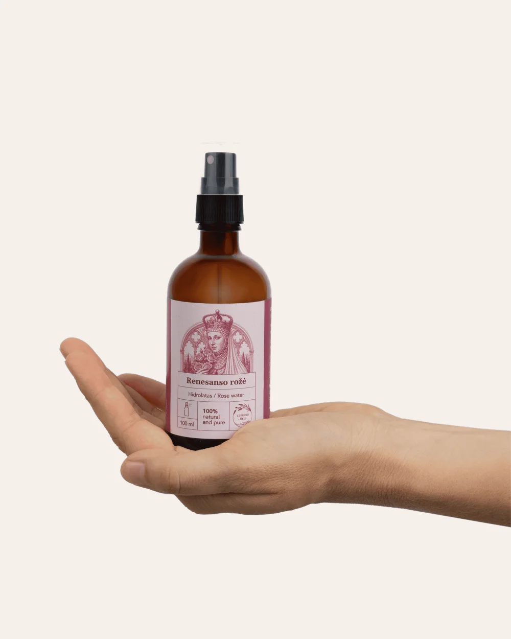 A bottle of “Renaissance Rose” rose hydrosol with a spray pump on an open palm