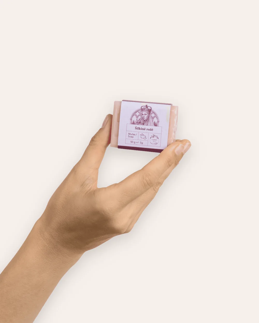 Ranka laiko mažą rausvą kieto muilo „Šilkinė rožė“ 50 g gabalėlį