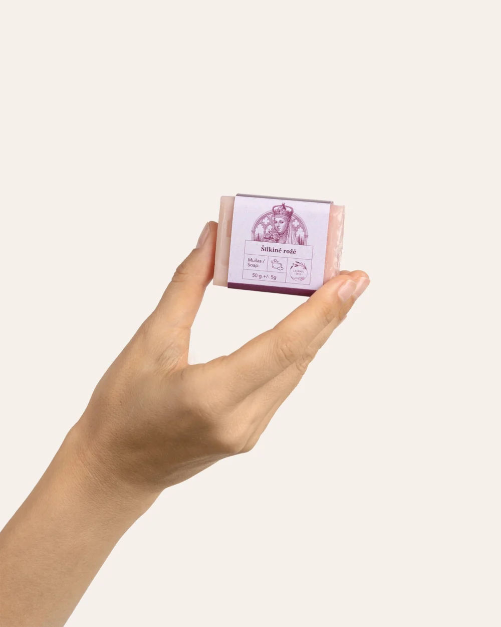 Ranka laiko mažą rausvą kieto muilo „Šilkinė rožė“ 50 g gabalėlį