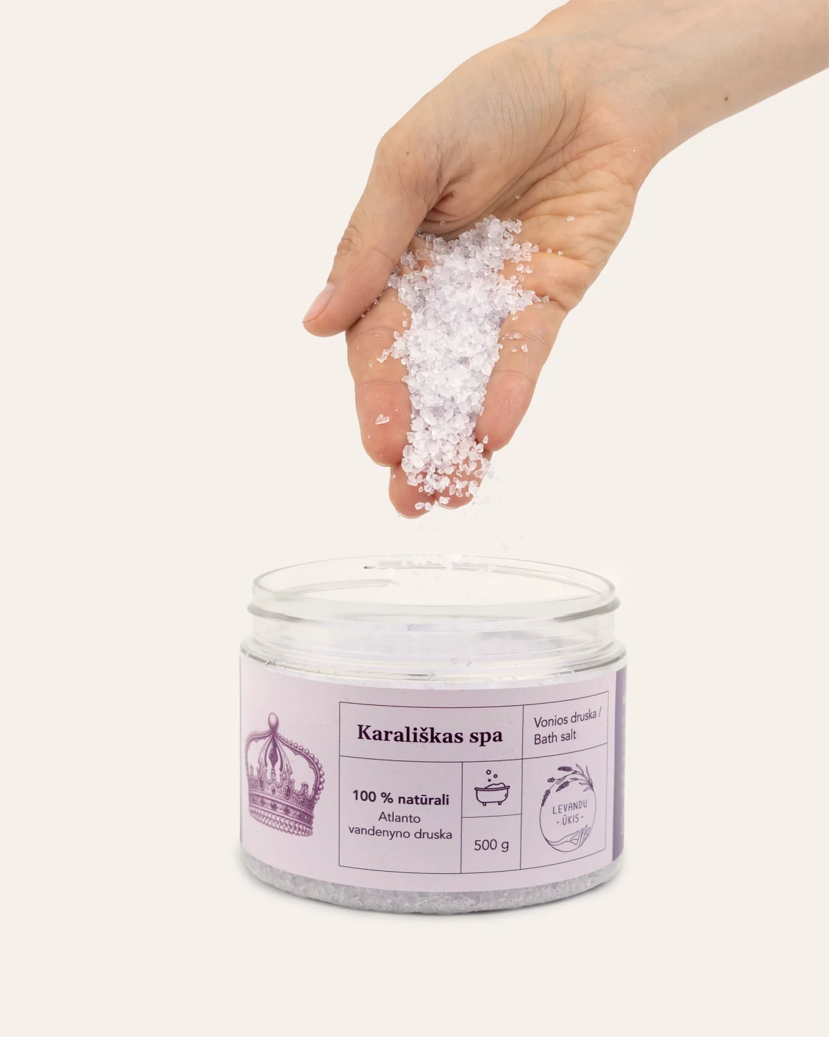 Hand pouring “Royal SPA” bath salt crystals into an open jar