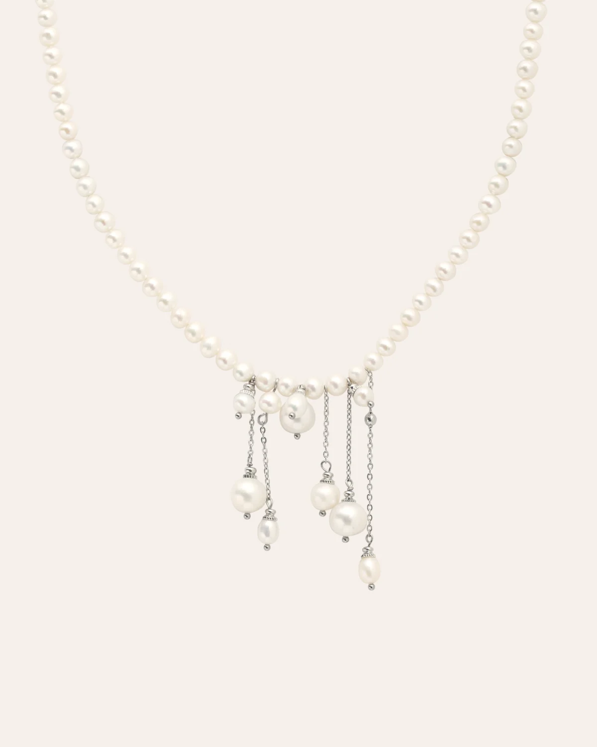 “The Queen's Dream” necklace of small pearls with hanging pearl drops on a light background