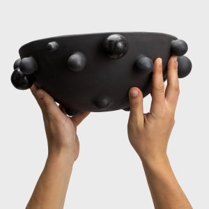 Large matte black “The Queen's Pearl Bowl” held in hands, side view