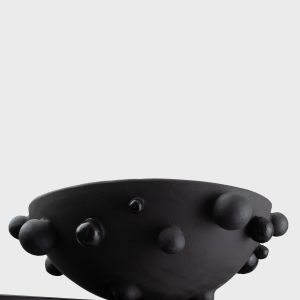 Side of the large matte black “The Queen's Pearl Bowl” with beads on the edge of a shelf