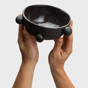 Small matte black “The Queen's Pearl Bowl” in two raised hands