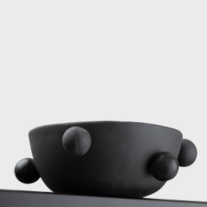 Side of the small matte black “The Queen's Pearl Bowl” with balls on a shelf