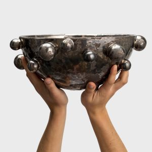 Large dark gold “The Queen's Pearl Bowl” in two hands, side view