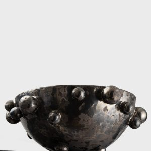 Side of a large dark gold “The Queen's Pearl Bowl” on the edge of a shelf