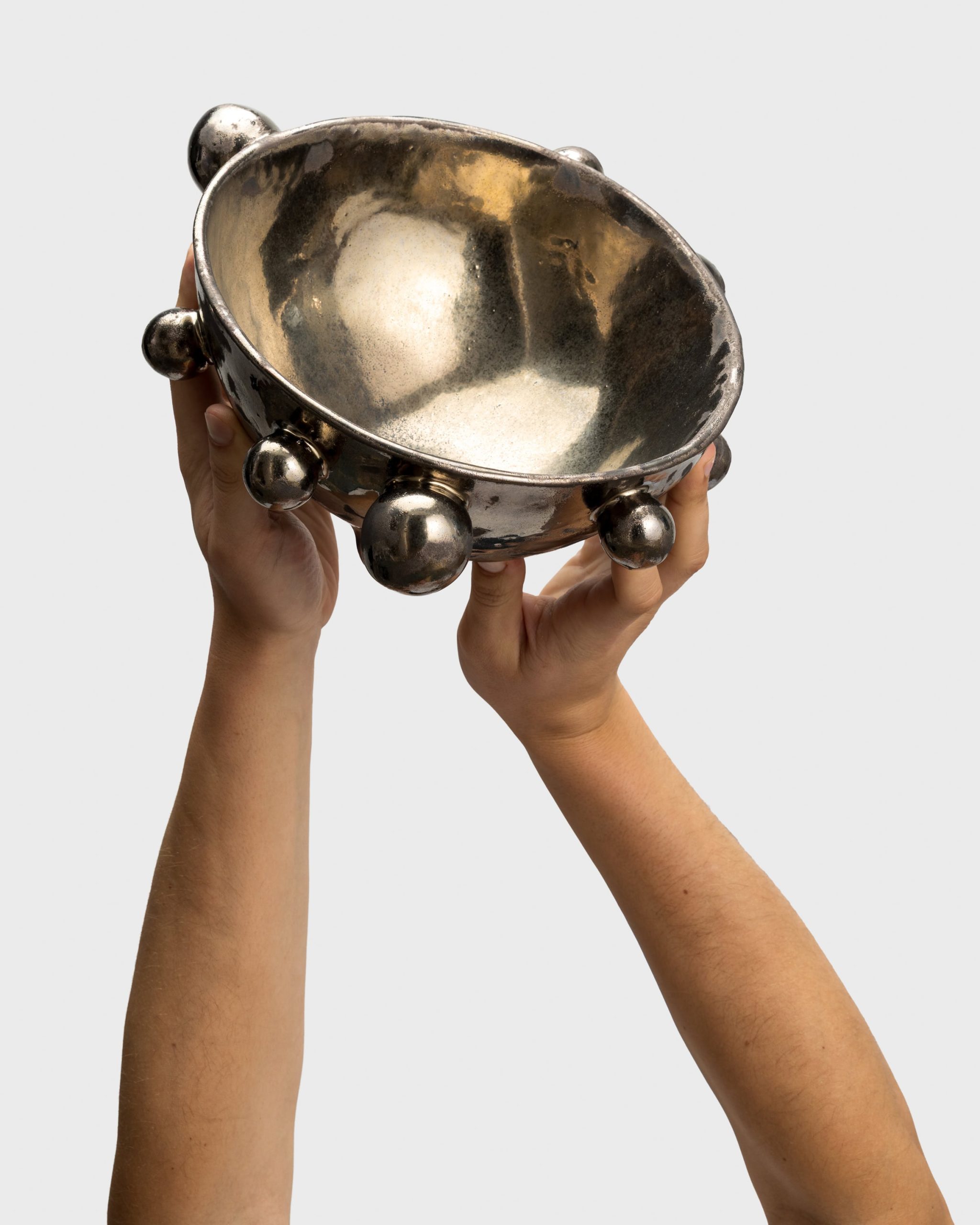 Dark gold “The Queen's Pearl Bowl” with beads, raised in two hands