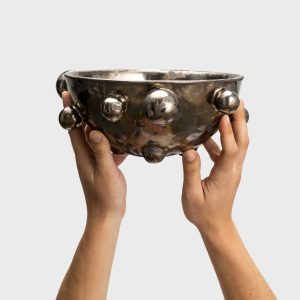 Medium dark gold “The Queen's Pearl Bowl” held in two hands, side view