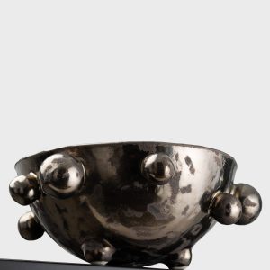 Side of a medium dark gold “The Queen's Pearl Bowl” on the edge of a shelf