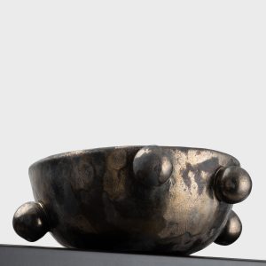 Side of the small dark gold “The Queen's Pearl Bowl” with balls on a shelf