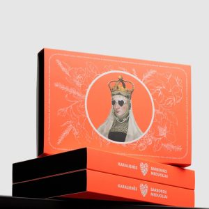 Orange boxes of “Queen Barbara's” gingerbread with the queen's portrait stacked on a black surface