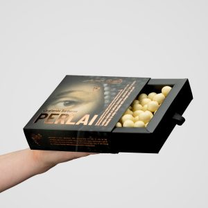 Pull-out box of “Queen Barbara's Pearls” with white sweets held in a hand