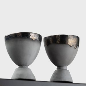 Black ceramic “Kings' Goblets” with glossy rims on a shelf, close-up