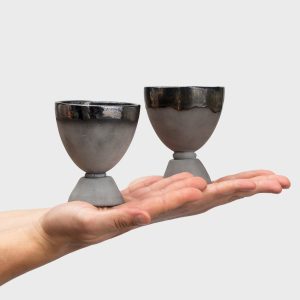 Two black ceramic “Kings' Goblets” on an open palm on a light background