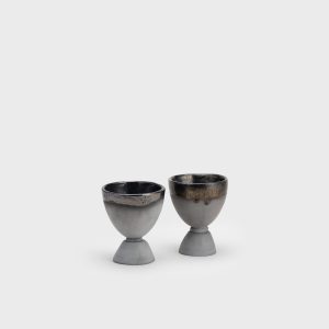 Two black ceramic “Kings' Goblets” from the side on a light background, seen from a distance