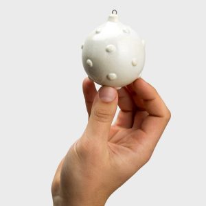 Hand holding a white collectible “Royal Pearl” Christmas ornament with a pearl relief