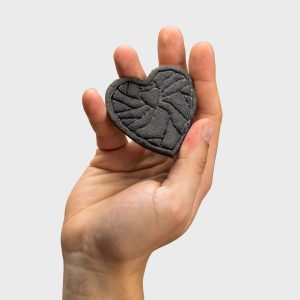 Dark heart-shaped “Crowned Heart Within a Heart” relief magnet held in a palm