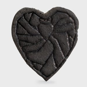 Close-up of the relief pattern on a dark heart-shaped “Crowned Heart Within a Heart” magnet