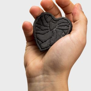 Close-up of the “Crowned Heart Within a Heart” magnet in the palm, showing the embossed line pattern
