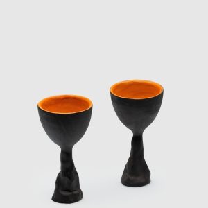 Two black Kings' Goblets with orange insides on a light background, front view