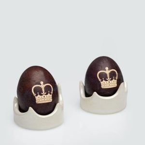 Pearl-coloured “Vilnius Crown” holders with dark eggs decorated with a crown drawing