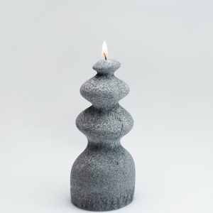 Anthracite wave-shaped candle “Queen Barbara” burning on a light background