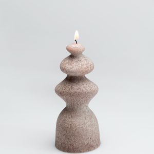 Powder-coloured wave-shaped “Queen Barbara” candle burning on a light background