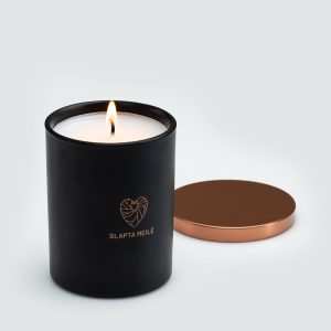 Lit “Slapta meilė” candle in a black jar with a heart logo and the copper-coloured lid beside it