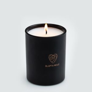 Lit “Slapta meilė” soy wax candle in a black jar with a copper-coloured heart logo