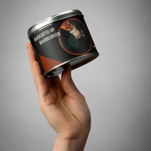 Hand holding a “Slapta meilė” sock gift tin with the words “Augustus and Barbara's”