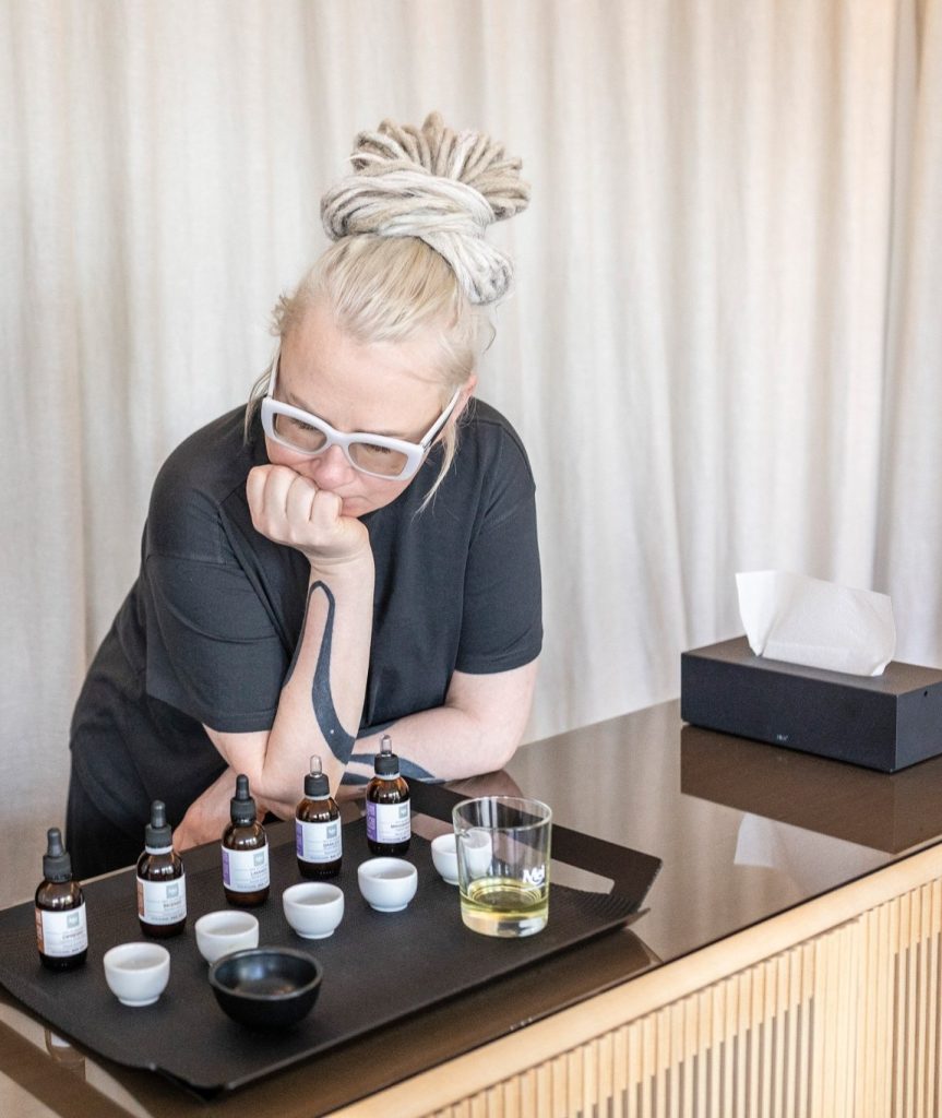 Woman choosing scents by a tray of bottles – “King Augustus' Hunt” ritual