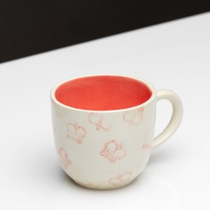 “Very Royal” ceramic mug with a red inside and pink crowns on a table