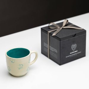 “Very Royal” mug with a green inside next to a black gift box with a ribbon