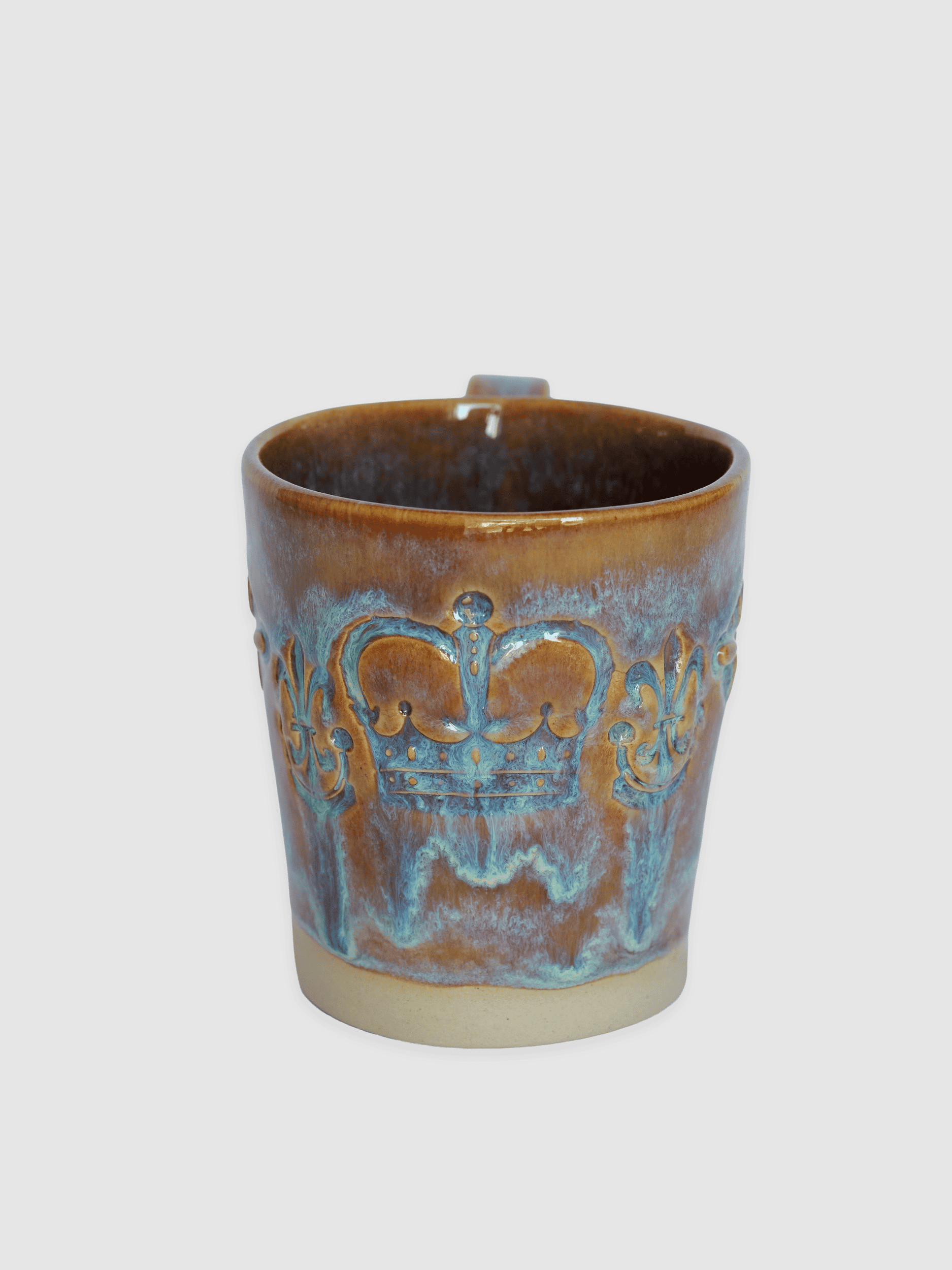 Brownish-blue “Audience” mug from the front with a relief crown and lilies