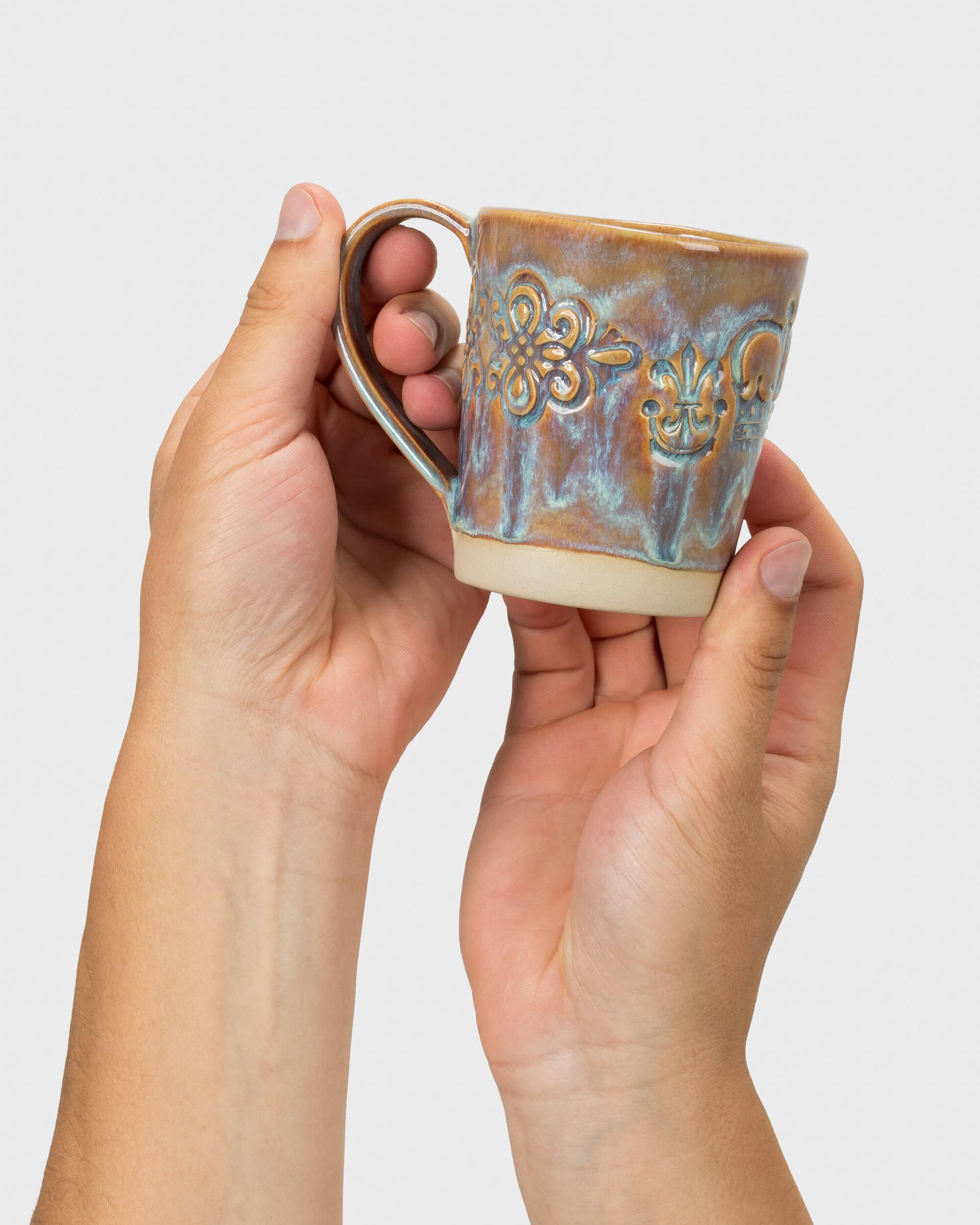Purple-tinted “Audience” mug with a handle and relief ornament in two hands